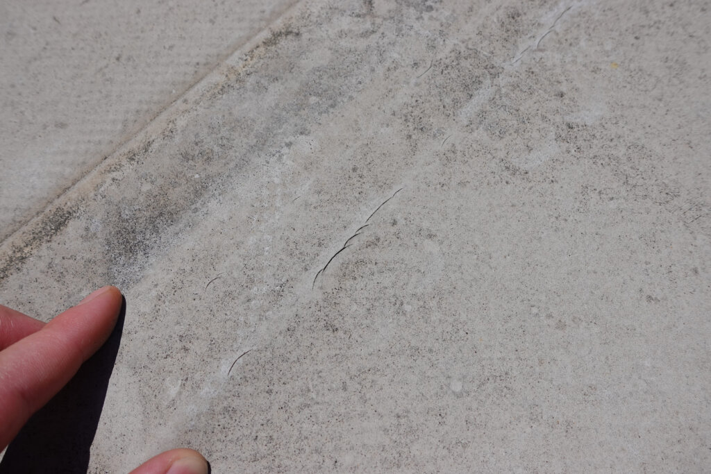 Riss in Betonoberfläche mit Hand als Größenvergleich