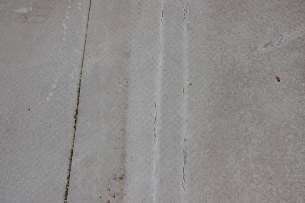 Graue Betonoberfläche mit Rissen und Fugen, verwitterte Textur mit Moos und Schmutz