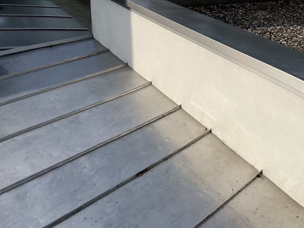 Graue Betontreppe mit weißer Wand und Kiessteinen an moderner Außentreppe