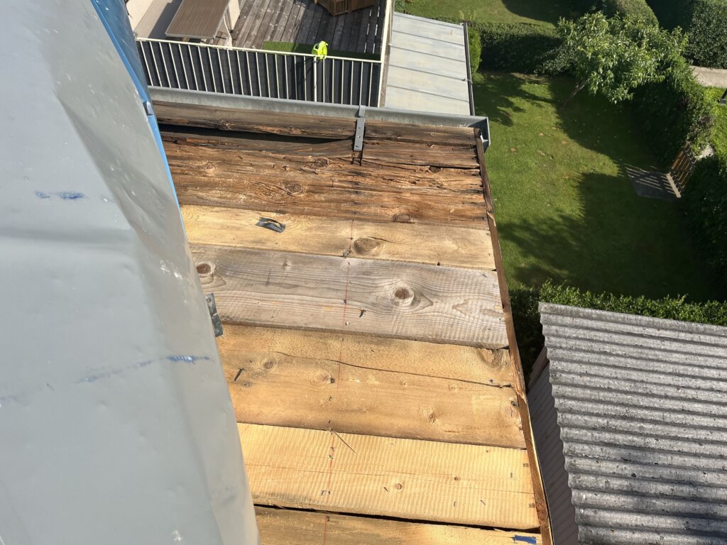 Holzterrasse von oben mit Blick auf Garten und Nachbargebäude, teilweise verwittertes Holz sichtbar