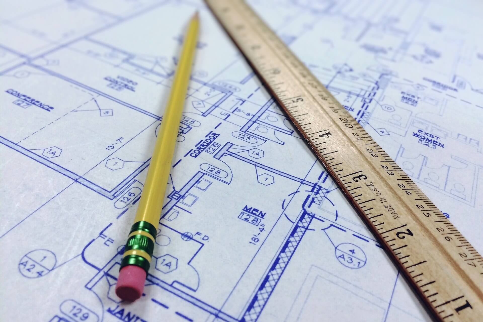 Architekturplan mit Bleistift und Holzlineal auf technischer Zeichnung